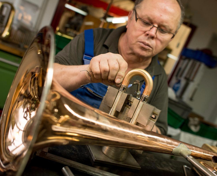 Handwerker bei Bearbeitung eines Blechblasinstruments