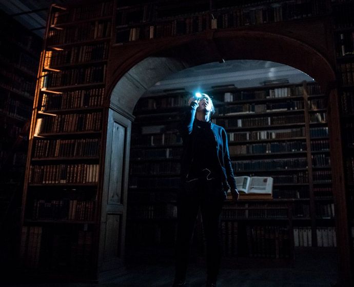 Filmszene aus "Enigma": Frau mit Taschenlampe in Bibliothek