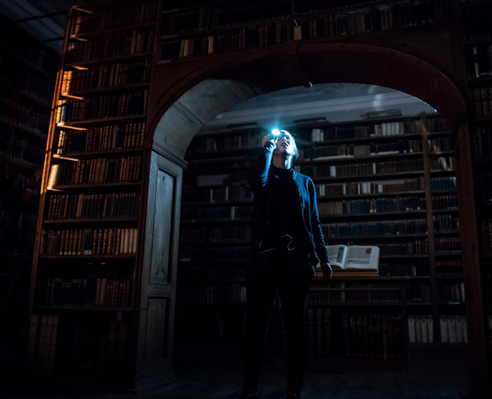 Filmszene aus "Enigma": Frau mit Taschenlampe in Bibliothek