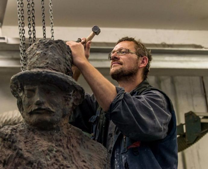 Mitarbeiter meißelt an einer Statue