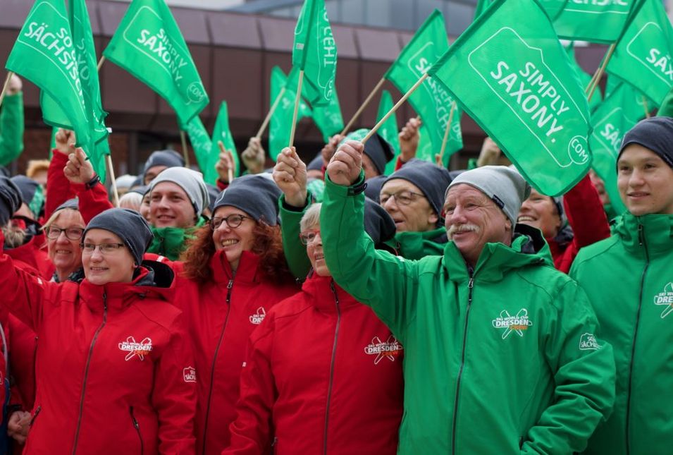 Die Organisatoren des Skiweltcups in grünen und roten Jacken mit "So geht sächsisch" Aufdruck.