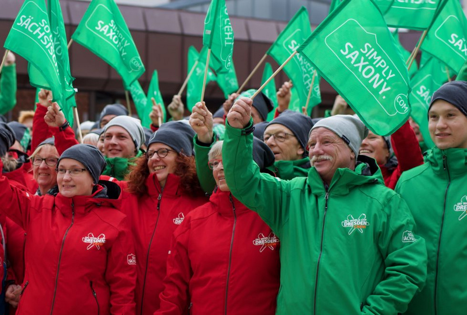 Die Organisatoren des Skiweltcups in grünen und roten Jacken mit "So geht sächsisch" Aufdruck.