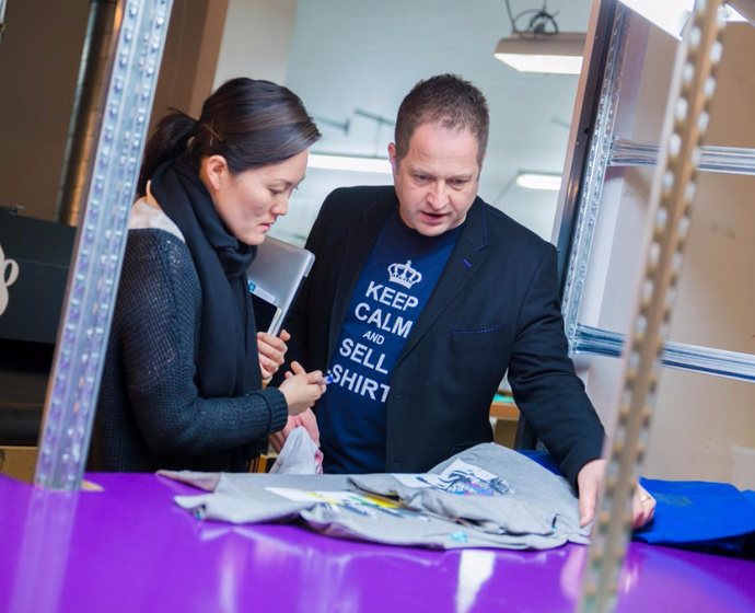 Philip Rooke mit Mitarbeiterin vor einem T-Shirt