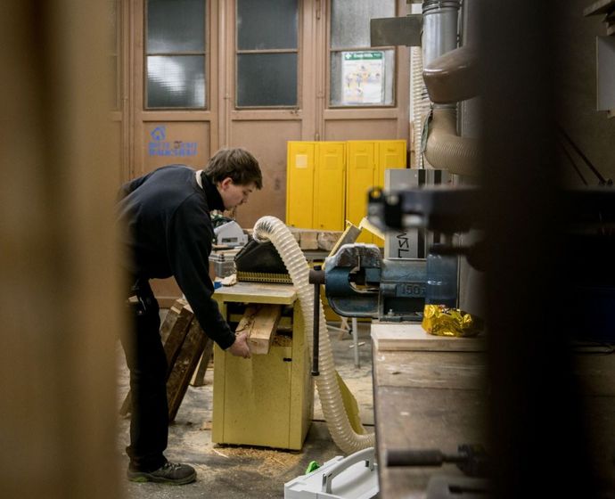 Mann an Gerät zur Holzbearbeitung in der Tischlerwerkstatt