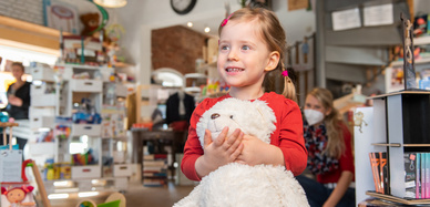 Mädchen mit Teddybär in den Armen in einem Spielzeugladen