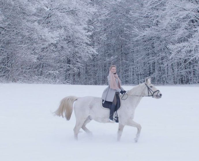 Reiterin auf weißem Pferd im Schnee