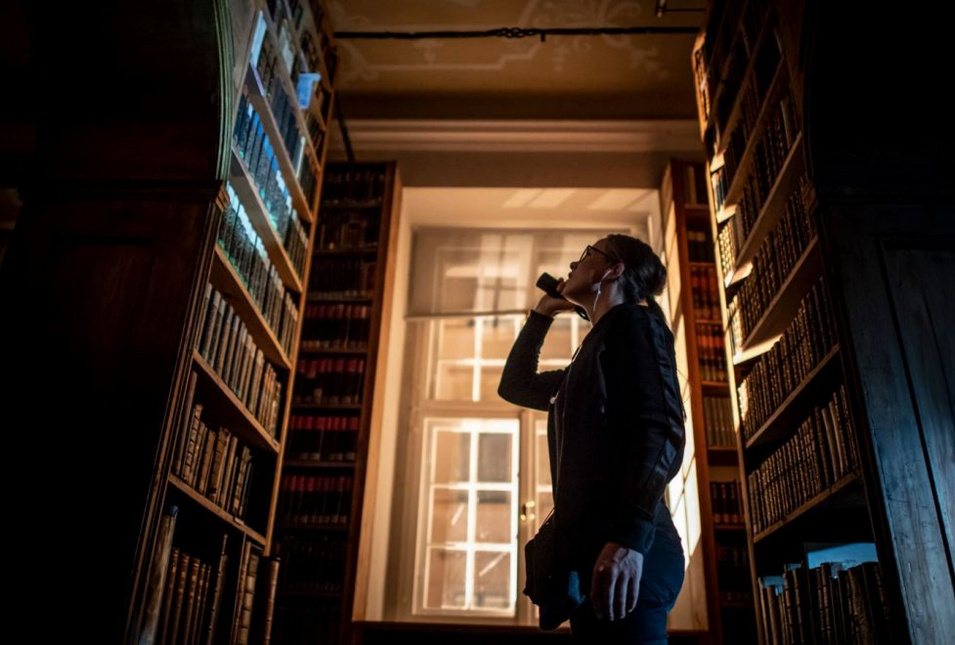 Szene aus dem Kurzfilm: Eine Frau leuchtet mit der Taschenlampe auf ein Bücherregal