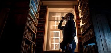 Szene aus dem Kurzfilm: Eine Frau leuchtet mit der Taschenlampe auf ein Bücherregal