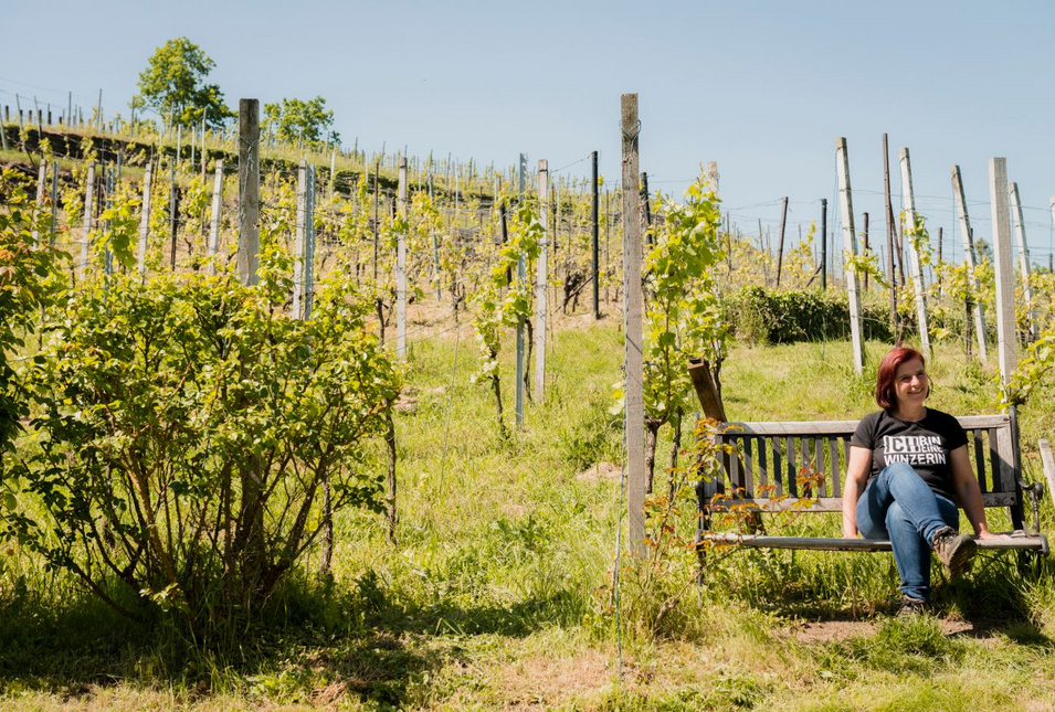 Winzerin Anja Fritz auf einer Bank am Weinhang